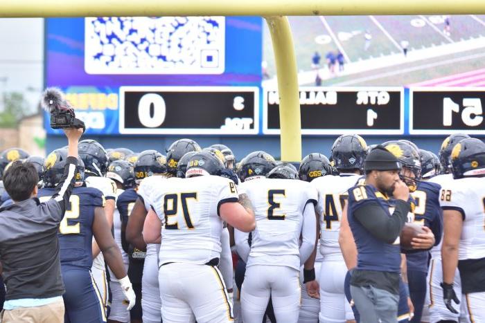 A group of football players around the goal post.